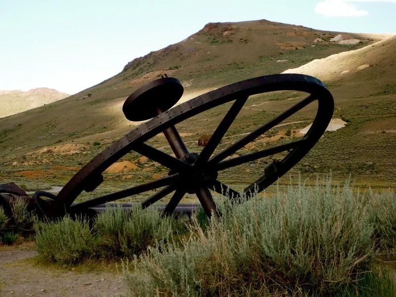 A weathered wagon wheel in the grass at Bodie