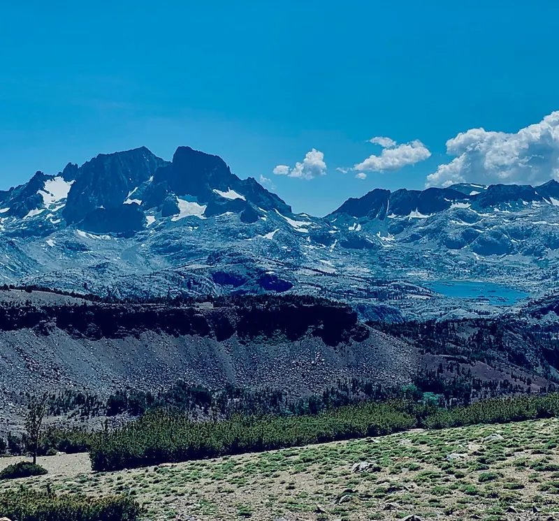 The view west from the summit of Carson Peak across the high Sierra, with jagged snow-streaked peaks and an alpine lake