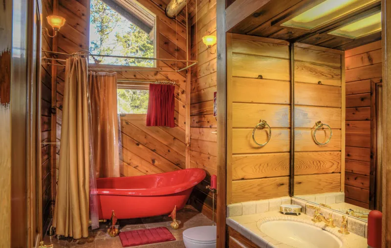 The Elsie Room's ruby-red claw-foot tub beneath a timber window