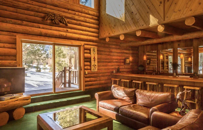 The Grand Room: leather couches by the deck doors, with the oak bar and its row of bucket stools beyond