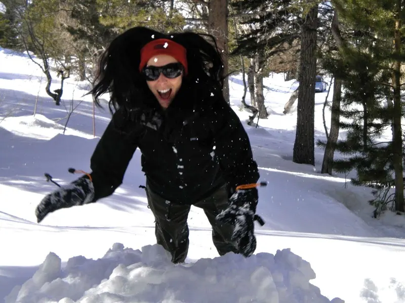 A guest laughing waist-deep in fresh snow outside the chalet