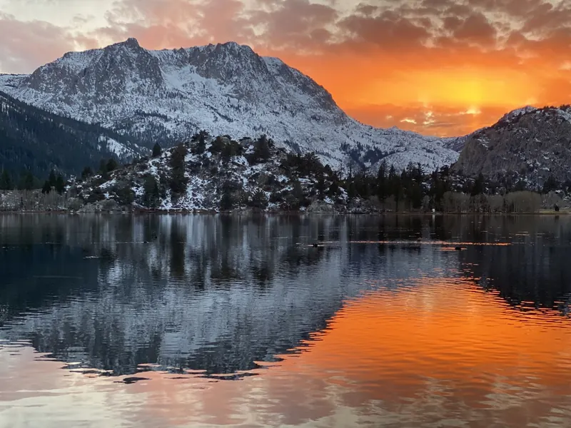 A fiery sunset over Gull Lake, with snow on the granite peaks reflected in the water